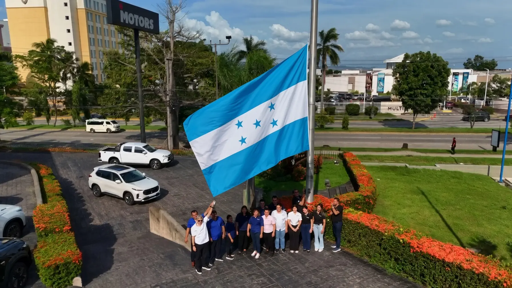 Equipo de iMotors Honduras junto a la bandera de Honduras